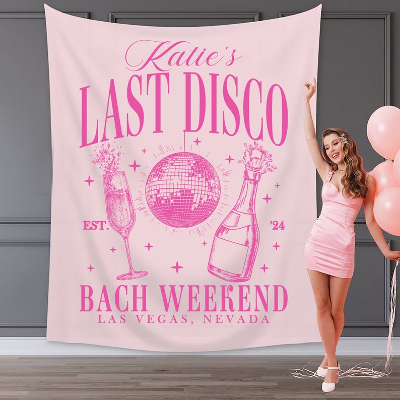 May include: Pink bachelorette party backdrop with the text "Katie's Last Disco" and "Bach Weekend Las Vegas, Nevada". The backdrop also features a disco ball, champagne bottle, and champagne flute.