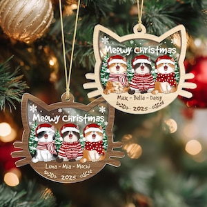 May include: Two wooden cat-shaped Christmas ornaments. Each ornament features three cartoon cats wearing Santa hats and red and white scarves and sweaters. The text "Meowy Christmas" is above the cats, with names and the year 2025 below.