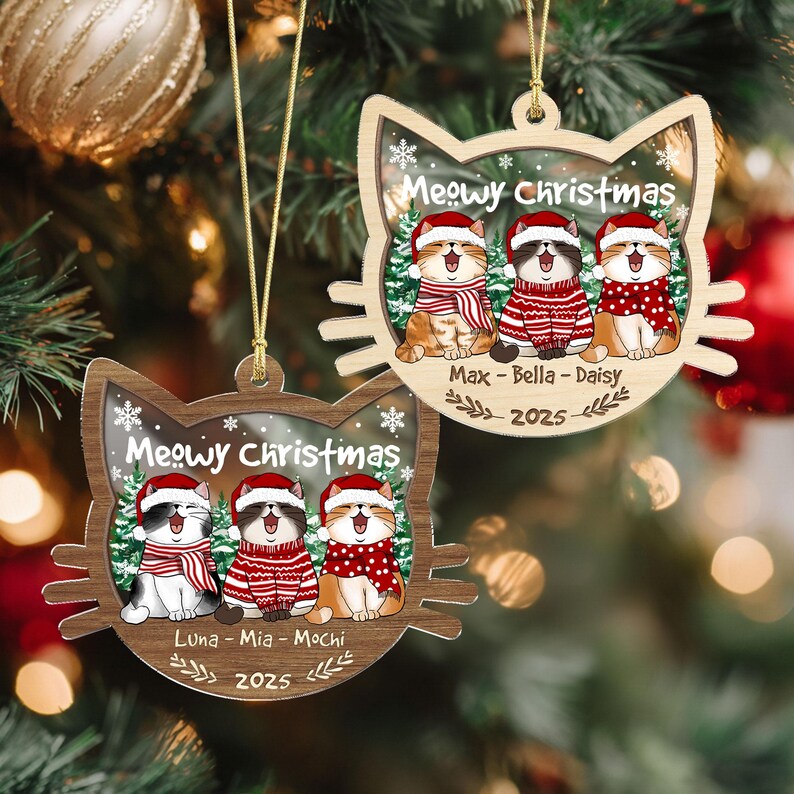 May include: Two wooden cat-shaped Christmas ornaments. Each ornament features three cartoon cats wearing Santa hats and red and white scarves and sweaters. The text "Meowy Christmas" is above the cats, with names and the year 2025 below.