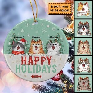 May include: A round, green and white Christmas ornament with three cats wearing Santa hats and reindeer antlers. The ornament says "Happy Holidays" and has a fishbone design. The breed and name of the cats can be changed.