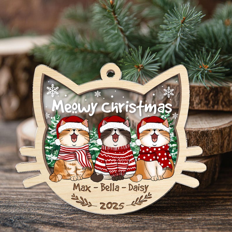 May include: Wooden cat-shaped Christmas ornament with the text "Meowy Christmas." The ornament features three cartoon cats wearing Santa hats and scarves. The names "Max - Bella - Daisy" and the year "2025" are also included.