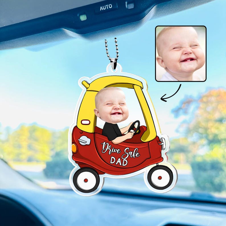 May include: A personalized car ornament featuring a smiling baby in a red and yellow cartoon car. The ornament has the text "Drive Safe DAD" and includes a small photo of the baby. The ornament hangs from a silver chain.