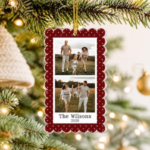 May include: A rectangular Christmas ornament with a scalloped edge, featuring a deep red border with white polka dots. The center displays two stacked photographs of a family in a field, with the text The Wilsons 2026 printed at the bottom.
