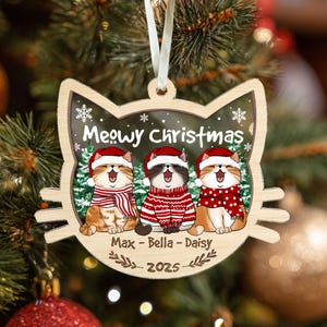 May include: Wooden cat-shaped Christmas ornament featuring three cartoon cats wearing Santa hats and scarves. The ornament reads "Meowy Christmas," with the names "Max - Bella - Daisy" and the year "2025" below.