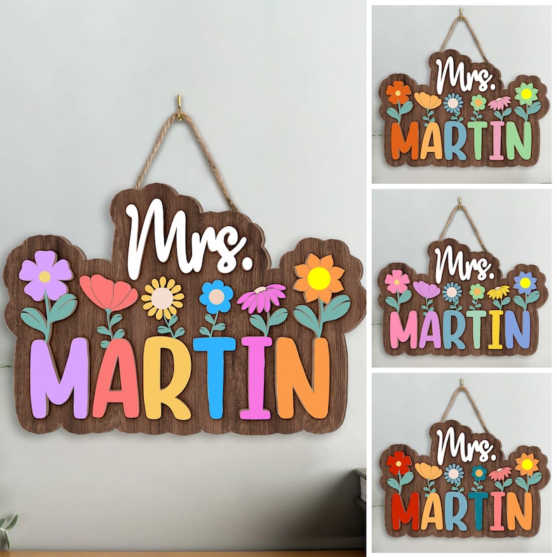 May include: Wooden sign with the text "Mrs. Martin" in white letters. The sign is decorated with colorful flowers and has a rustic brown finish.