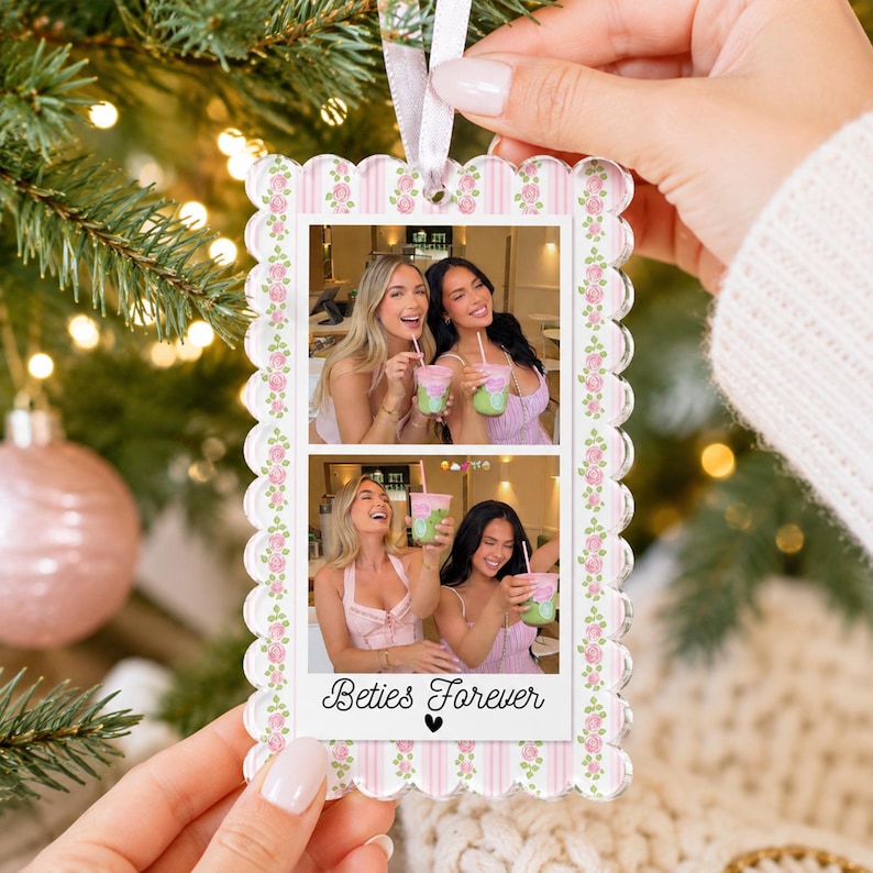 May include: A rectangular scalloped acrylic ornament featuring a pink and white striped border with a floral rose pattern. The center displays two stacked photos of two people holding green drinks, with the text Beties Forever below.
