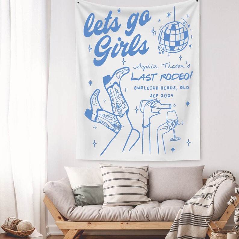 May include: A white tapestry with blue text and illustrations. The text reads "lets go Girls Sophia Thason's LAST RODEO! BURLEIGH HEADS, QLD SEP 2024". The illustration includes a disco ball, two pairs of cowboy boots, and two hands holding a bottle of wine and a glass of wine.
