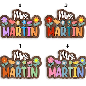 May include: Four wooden signs with the text "Mrs. Martin" in colorful letters. Each sign has a different arrangement of colorful flowers.