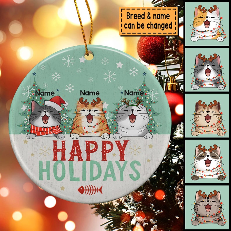May include: A round, green and white Christmas ornament with three cats wearing Santa hats and reindeer antlers. The cats are in front of Christmas trees and the ornament says "Happy Holidays".
