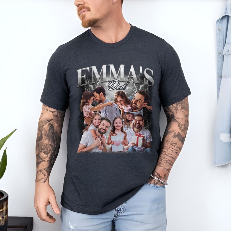 Peut inclure: Un t-shirt gris fonc&eacute; avec un imprim&eacute; graphique d'un homme avec ses enfants. Le graphique comprend le texte "EMMA'S Dad" en lettres argent&eacute;es avec des &eacute;clairs.