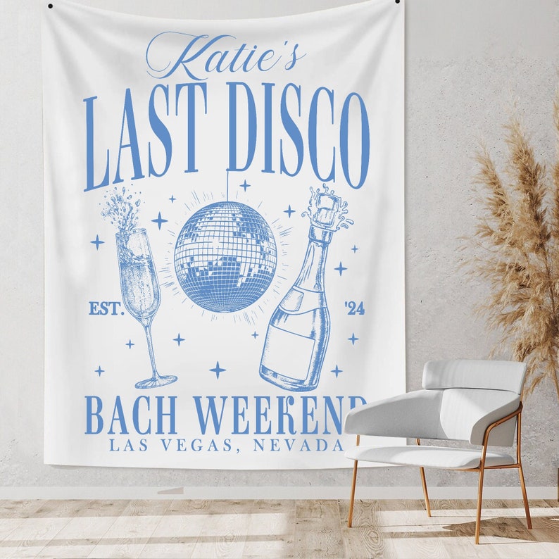 May include: A white banner with blue text that reads "Katie's Last Disco" with a disco ball, champagne bottle and glasses. The text below reads "Bach Weekend Las Vegas, Nevada".