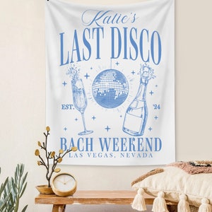 May include: White tapestry with blue text that reads "Katie's Last Disco Est. '24 Bach Weekend Las Vegas, Nevada". The tapestry also features a blue illustration of a champagne flute, a disco ball, and a bottle of champagne.