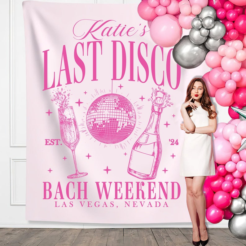 May include: Pink bachelorette party backdrop with the text "Katie's Last Disco Bach Weekend Las Vegas, Nevada" and a pink disco ball, champagne bottle, and champagne flute.