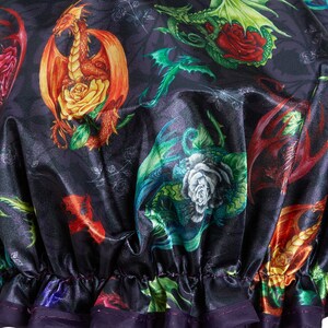 May include: A black satin shower cap with a colorful print of dragons and roses. The cap has a purple elastic band.
