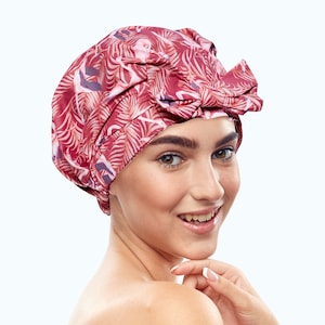 May include: A red shower cap with a pink flamingo and leaf print. The cap has a bow on top.