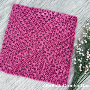 May include: A pink crocheted square with a detailed pattern. The square is made with a single crochet stitch and has a delicate, lacy look.