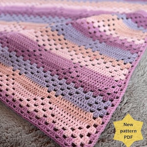Puede incluir: Una manta de ganchillo hecha a mano en tonos de rosa, lavanda y melocotón. La manta presenta un patrón de granny square con un aspecto texturizado. El texto "New pattern PDF" está en una estrella amarilla. El nombre de la tienda Etsy "AllaBellaLondon" está en la parte inferior.