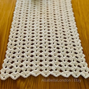 Könnte beinhalten: Cremefarbener Tischläufer aus Häkelarbeit mit offenem Gewebe. Der Läufer hat einen gewellten Rand und ein Rautenmuster. Der Etsy-Shop-Name "AllaBellaLondon | Etsy" ist sichtbar. Dekoratives Stück für Esstisch oder Kommode.