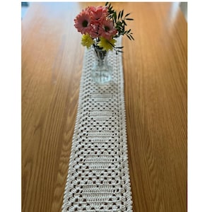 May include: A cream-coloured rectangular crochet table runner featuring a repeating granny heart pattern. The text Granny Hearts Table Runner Crochet Pattern by AllaBellaLondon Etsy&Ravelry is visible at the top and bottom of the image.