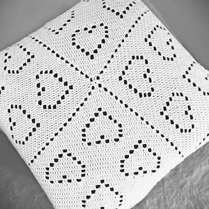 May include: White crocheted throw pillow with a black and white geometric pattern.