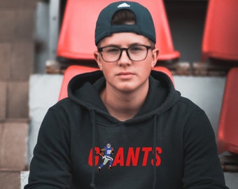 May include: A black hoodie with a red "GIANTS" graphic and a cartoon football player wearing a blue jersey. The hoodie has a drawstring hood and a kangaroo pocket.
