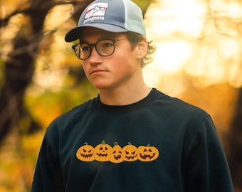 May include: A black sweatshirt with a row of five orange jack-o'-lantern faces printed on the front.