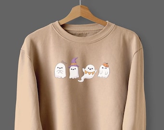 May include: A tan sweatshirt with a graphic of five ghosts wearing Halloween costumes. The ghosts are wearing a witch hat, a banner, and a pumpkin hat.