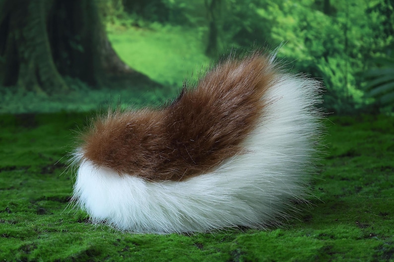 May include: A fluffy, faux fur tail in brown and white. The tail is a mix of brown and white fur, with the brown fur at the top and the white fur at the bottom. The tail is likely for a costume or cosplay.