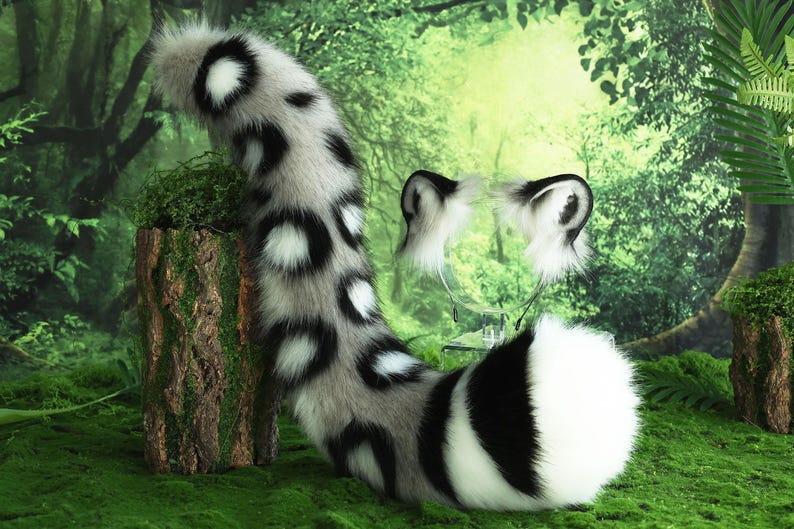 May include: A white and black spotted faux fur tail with a matching white and black spotted headband. The tail is long and fluffy, and the headband has large, floppy ears.