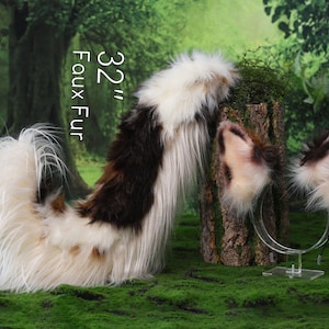 May include: A 32-inch faux fur tail with long white, brown, and black fibers, paired with a matching pair of animal-style ears attached to a clear plastic headband. The set features a multi-colored, shaggy texture throughout the design.