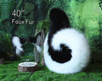 May include: A set of faux fur animal ears on a headband and a long 40" faux fur tail. The ears are black and white with pointed tips. The tail is curled into a spiral shape, featuring a thick black base that transitions into a large white tip.