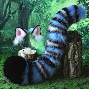 May include: A furry costume set featuring a black and blue striped tail and matching cat ears with pink inner ears. The tail is long and curved, and the ears are attached to a clear headband. The set is designed for cosplay or costume use.