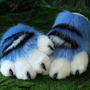 Peut inclure: Une paire de pieds de costume en forme de pattes, bleus et blancs. La fourrure bleue présente des rayures noires et blanches, et les pattes ont une fourrure blanche avec des griffes noires. Les pieds de costume sont conçus pour ressembler à des pattes d'oiseau.
