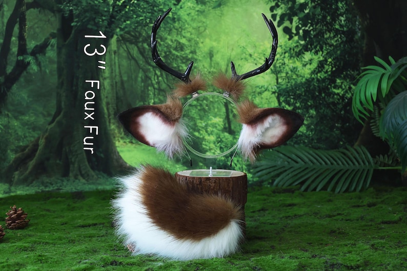 May include: A set of faux fur deer ears and tail. The ears are brown and white with black antlers. The tail is brown and white. The text "13" Faux Fur" is printed vertically on the left side of the image. The set is displayed on a wooden stand.