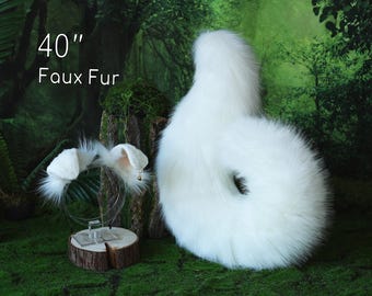 May include: A set consisting of a pair of white faux fur animal ears on a headband and a long, white faux fur tail. The text 40" Faux Fur is visible in the upper left corner. The items are white with long, soft, synthetic fur texture.