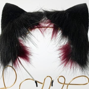 May include: Black cat ears headband with burgundy tips. The headband is made of faux fur and is attached to a metal headband.