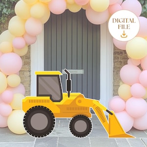 May include: A yellow toy construction vehicle with a black cab and a scoop. The vehicle is in front of a backdrop of pink and yellow balloons.