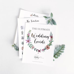 May include: A printable wedding guide with a floral wreath design. The guide includes sections for the caterer, timeline, and other wedding planning details. The text reads "The Ultimate Wedding Guide by The Maby Studio."