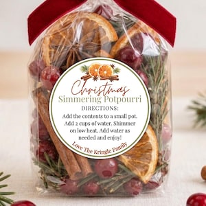 May include: A clear plastic bag filled with dried orange slices, cinnamon sticks, cranberries, and pine needles. A deep red velvet ribbon is tied at the top. A round label reads: Christmas Simmering Potpourri DIRECTIONS: Add the contents to a small pot. Add 2 cups of water. Shimmer on low heat. Add water as needed and enjoy! Love The Kringle Family.