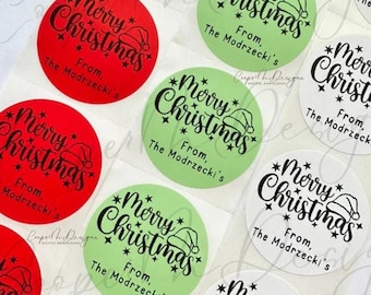 May include: A sheet of round, white stickers with black text that reads "Merry Christmas" with a Santa hat graphic and "From, The Modrzecki's". Some stickers are red and some are green.
