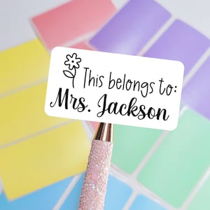 May include: White label with a black line drawing of a flower and the text "This belongs to: Mrs. Jackson".