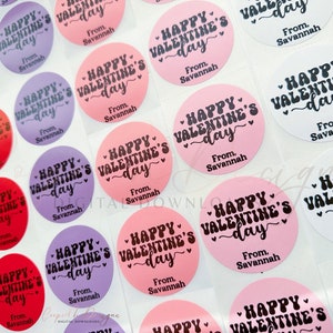 Puede incluir: Surtido de pegatinas redondas para el D&iacute;a de San Valent&iacute;n con el texto "Happy Valentine's Day" en fuente de letra cursiva negra sobre fondo rosa, rojo, morado y blanco. Las pegatinas tambi&eacute;n incluyen el texto "From, Savannah".