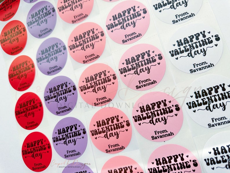 Puede incluir: Surtido de pegatinas redondas para el D&iacute;a de San Valent&iacute;n con el texto "Happy Valentine's Day" en fuente de letra cursiva negra sobre fondo rosa, rojo, morado y blanco. Las pegatinas tambi&eacute;n incluyen el texto "From, Savannah".