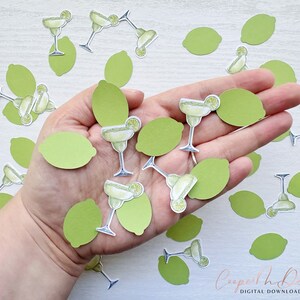 May include: A hand holding a variety of green lime and margarita glass confetti. The confetti is made of paper and features a lime wedge and a margarita glass with a lime wedge garnish.