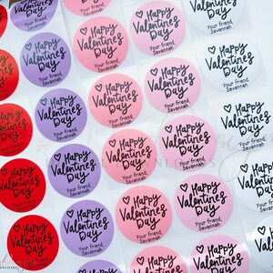 Puede incluir: Una hoja de pegatinas redondas para el D&iacute;a de San Valent&iacute;n con el texto "Happy Valentine's Day" en escritura cursiva negra. Las pegatinas son de varios colores, incluyendo rosa, rojo, blanco y morado. El texto "Your friend, Savannah" est&aacute; impreso en cada pegatina.
