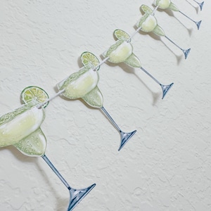 May include: A string of green margarita glass cutouts with lime wedges, perfect for a festive party decoration.