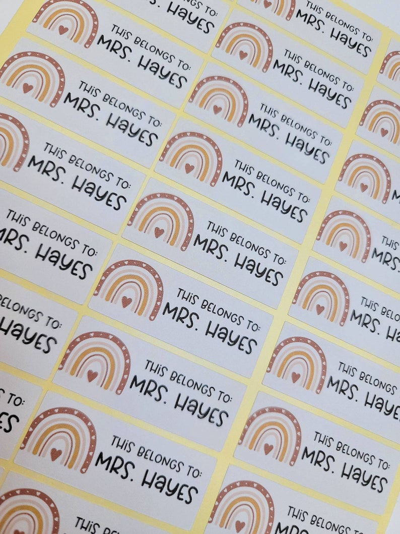 May include: A set of 12 rectangular stickers with a rainbow design and the text "This belongs to: MRS. HAYES". The stickers are on a yellow background.