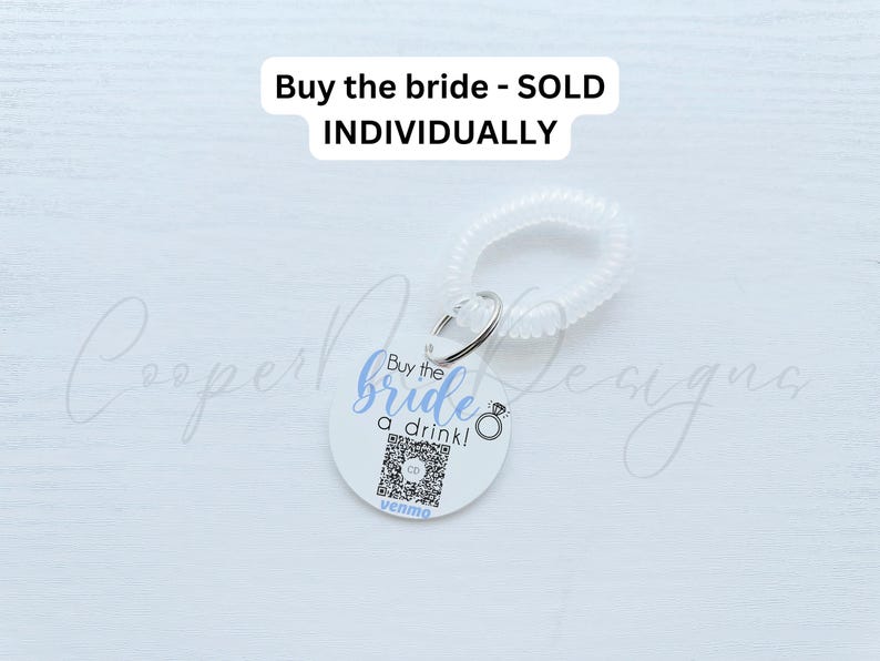 May include: White round keychain with a blue and black design that says "Buy the bride a drink!" with a ring icon and a Venmo logo. The keychain is attached to a clear plastic coil.