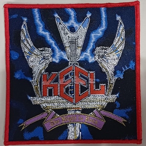 以下が含まれることがあります： 銀と赤のダイヤモンド型に「KSL」という文字が書かれた、赤、白、青の刺繍パッチ。パッチには、翼のある銀のギターと、ピンクのリボンに「The Right to Rock」という文字が書かれている。