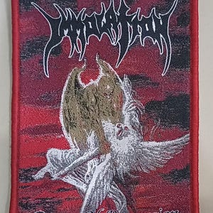 May include: Embroidered patch with a red border and a detailed design. The patch features the band name "Immolation" in white, stylized lettering above an illustration of a winged figure. The text "Dawn Of Possession" is below the illustration.
